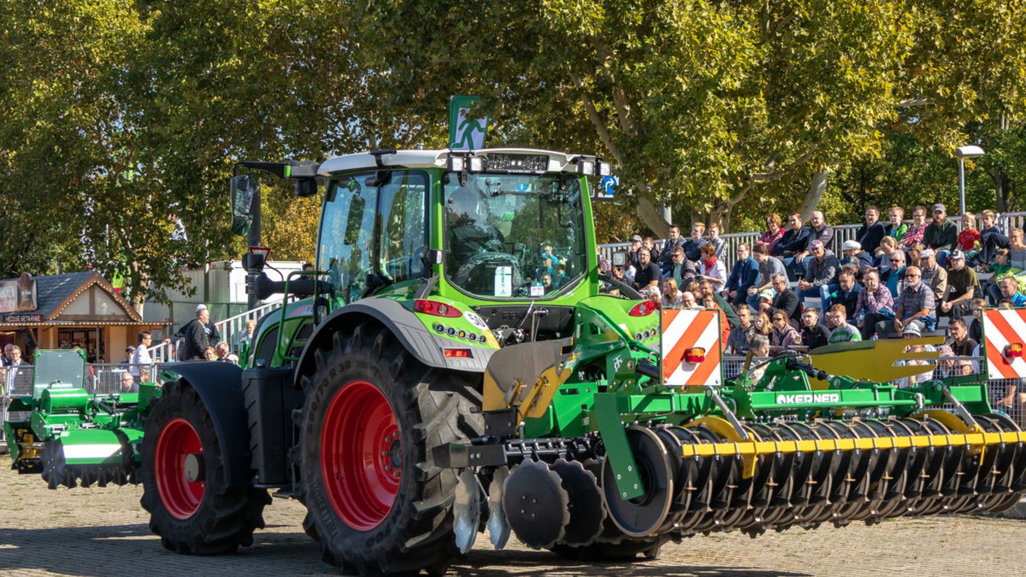 Ein großer Traktor fährt mit angehängten Arbeitsgeräten vorbei