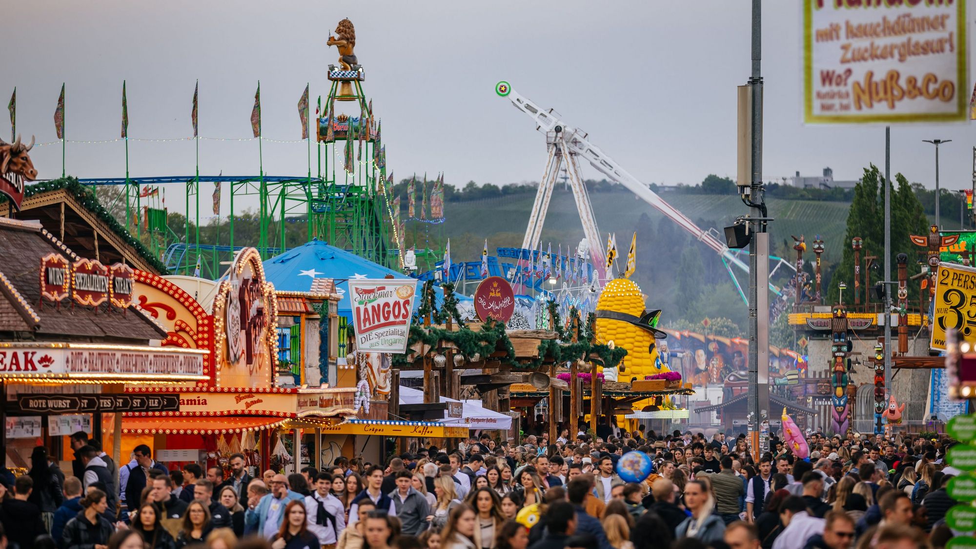 Buntes Treiben in einer der Gassen des Stuttgarter Frühlingsfestes mit vielen Menschen und Buden
