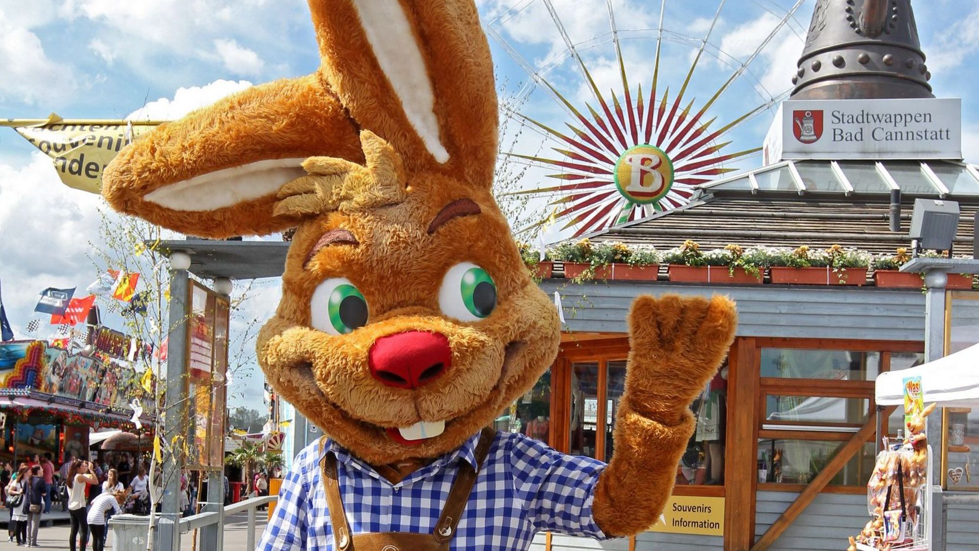 Das Maskottchen des Cannstatter Wasen "Wasi" winkt fröhlich vor der Cannstatter Kanne in die Kamera