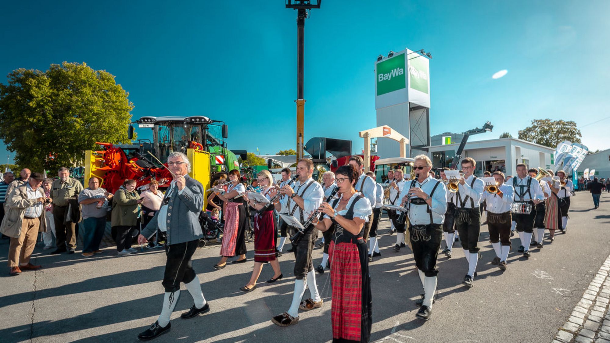 Eine Trachtengruppe mit Musik läuft auf einem Weg an Zuschauern vorbei